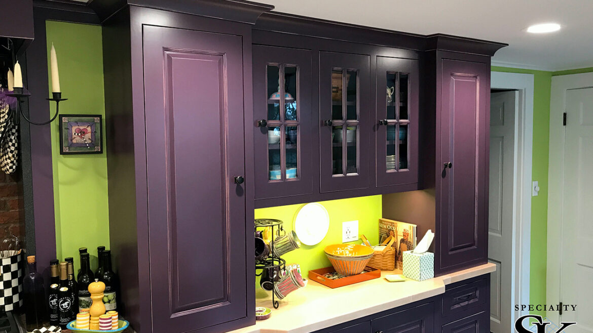 Purple kitchen cabinets with glass doors, lime green walls, and under-cabinet lighting, featuring kitchen accessories.