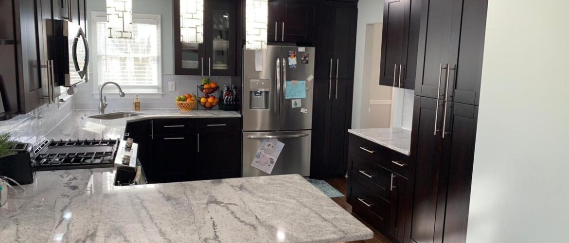 Modern kitchen with dark wood cabinets, granite countertops, stainless steel appliances, and pendant lighting.