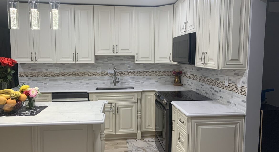 Modern kitchen with white cabinets, marble countertops, stainless steel appliances, pendant lights, and floral decor.