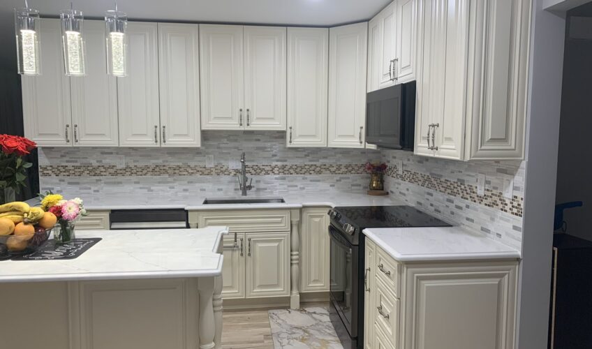 Modern kitchen with white cabinets, marble countertops, stainless steel appliances, pendant lights, and floral decor.