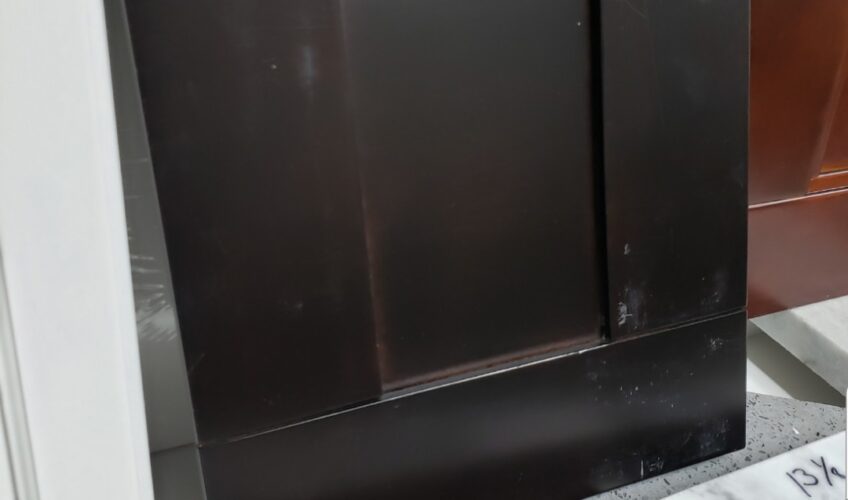 Dark brown kitchen cabinet door with a simple rectangular design, leaning against a white surface.